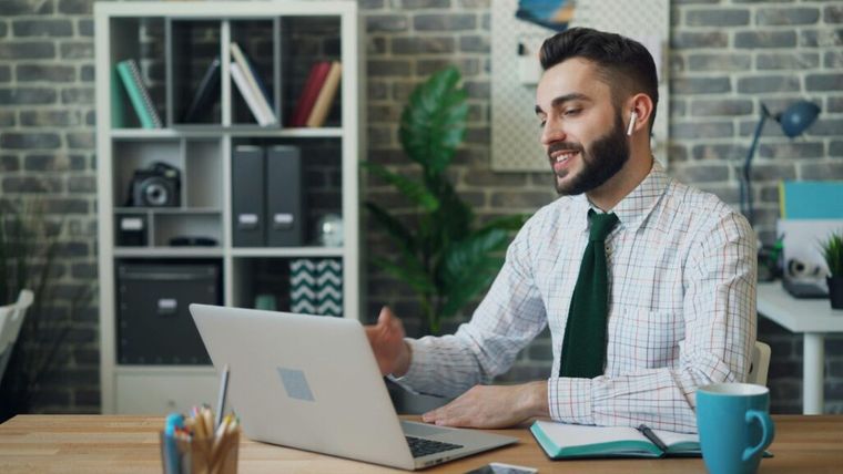 An office worker smiles while looking at a laptop screen, highlighting tax firm efficiency.