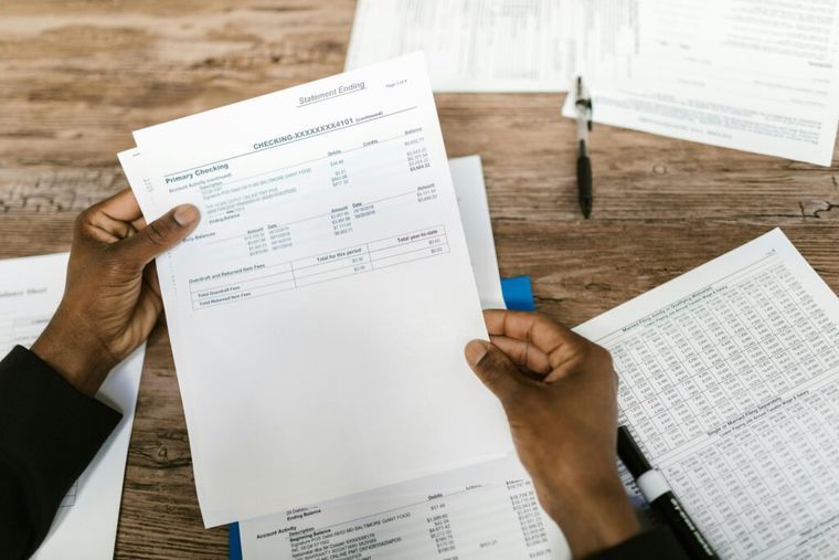 A person holding a sheet of white printer paper, representing the importance of documentation in managing multiple 1099s efficiently.