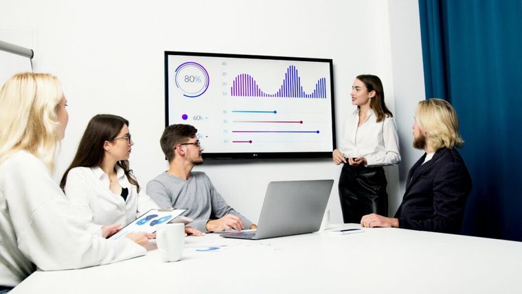 A woman presenting international trade data during a business meeting, representing global duty reduction strategies and HTS compliance.