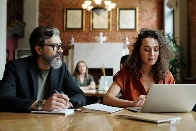 Two people working together on a laptop and notes to plan charitable tax deductions.
