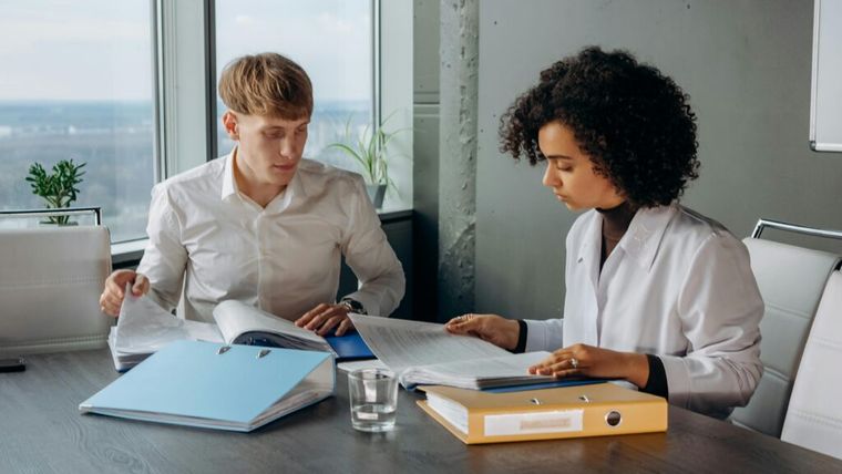 Two professionals review colorful financial charts and graphs, highlighting the growing challenge for accountants to analyze complex data sets and provide actionable insights in 2025.