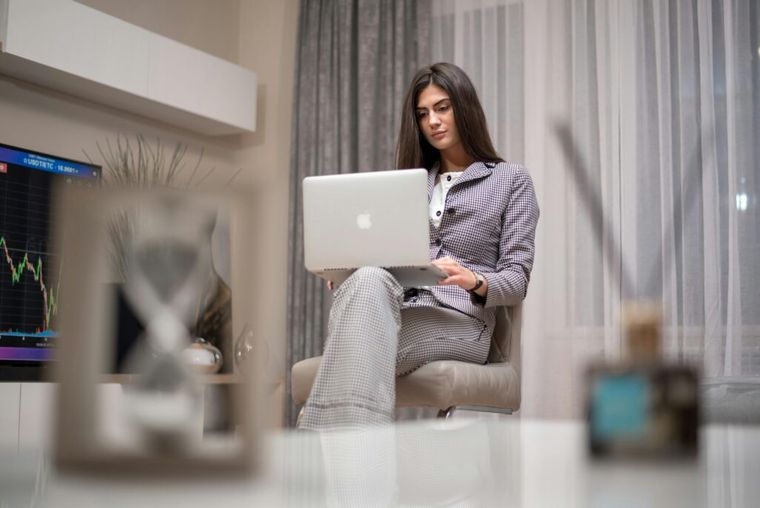 A woman sitting on a chair, using a laptop to seek investor tax advice, showcasing a focused and engaged expression while working on her financial strategies.