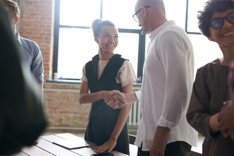 A man and woman shaking hands, symbolizing improved client satisfaction.
