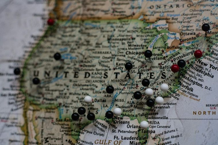 A detailed map of the United States pinned to a wall, symbolizing state-by-state differences in tax laws, business regulations, and strategic planning considerations for remote workers and business owners alike.