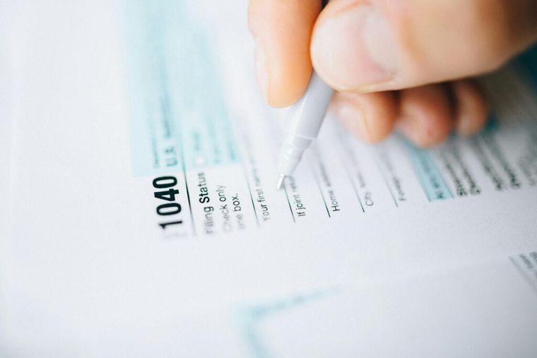 A close-up of a pen and tax forms with handwritten notes—symbolizing the importance of tracking IRS deadlines for quarterly estimated tax payments.