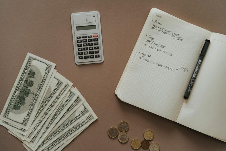 An image of cash next to a notebook and calculator.
