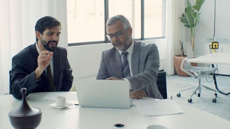 Business professionals collaborating on a laptop in a modern office setting.