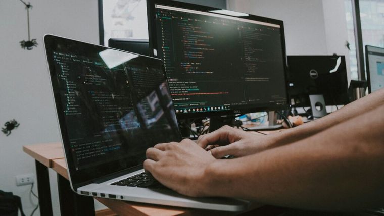 Person working on a computer with data charts visible on the screen.