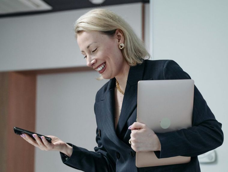 A woman in a black blazer using a laptop and smartphone, representing AI integration in CPA firms.