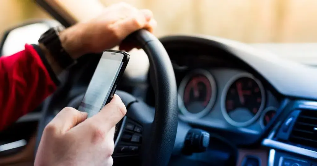 an image of hand on the phone and steering wheel