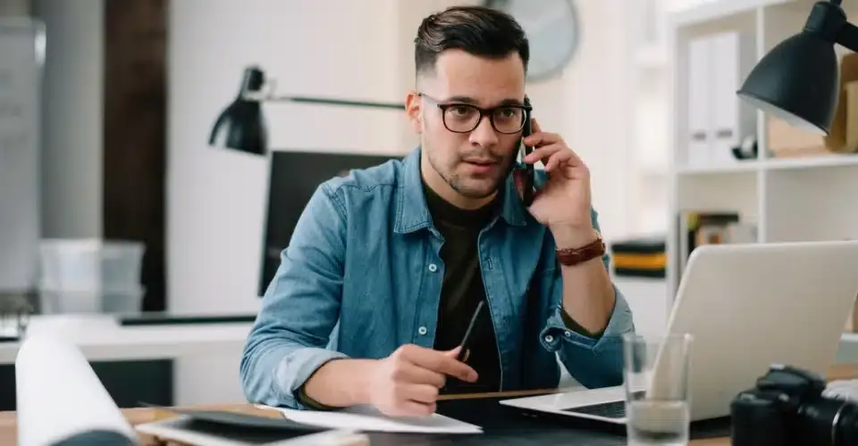 a man wearing a eye glasses and holding a phone