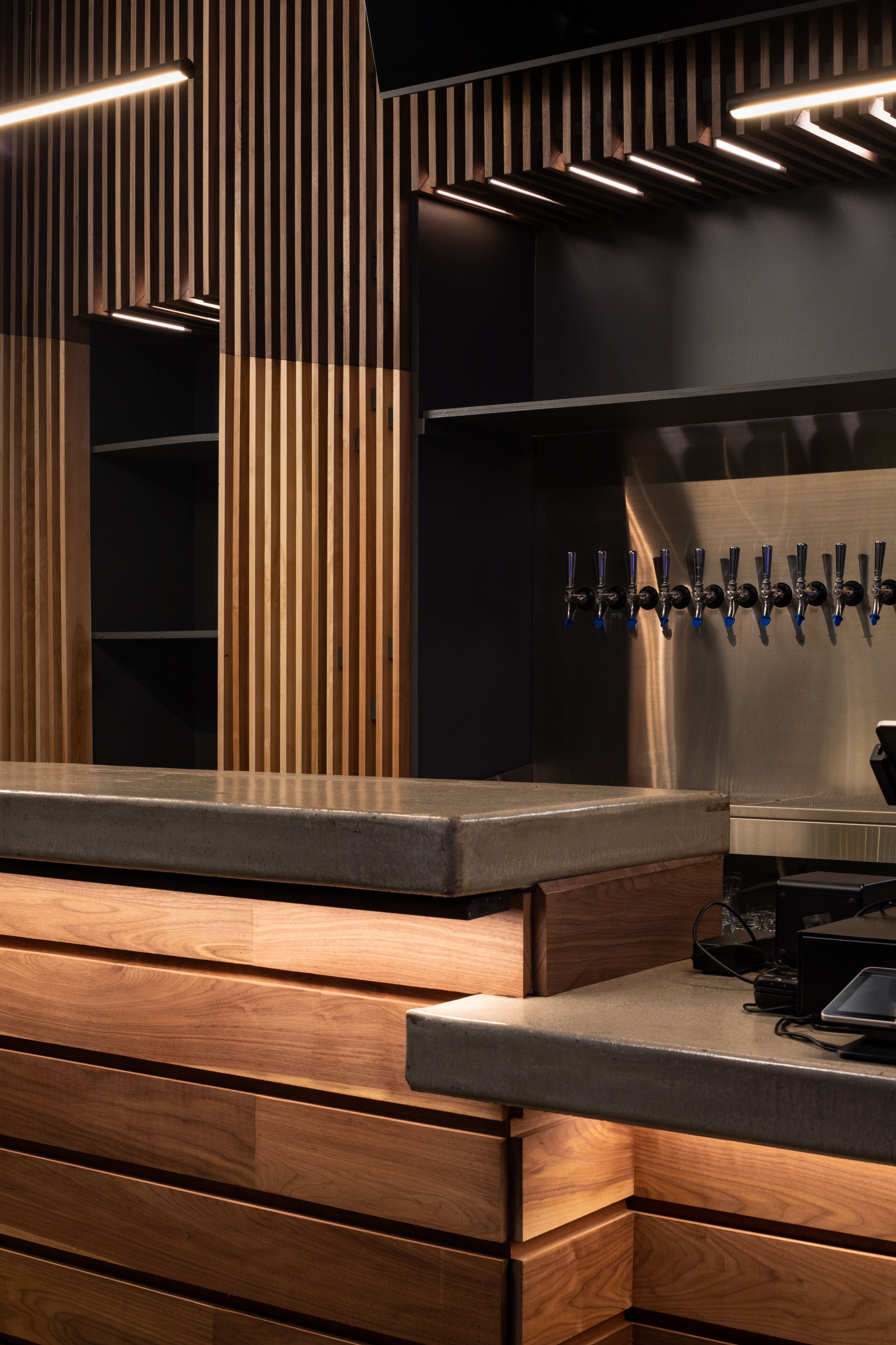 03 — Tap wall. Ten taps in line against stainless: everything that gets wiped a thousand times was left smooth on purpose.