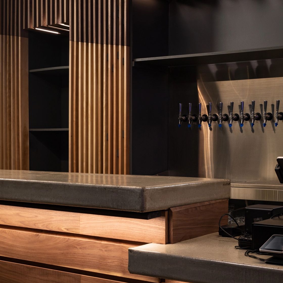 03 — Tap wall. Ten taps in line against stainless: everything that gets wiped a thousand times was left smooth on purpose.
