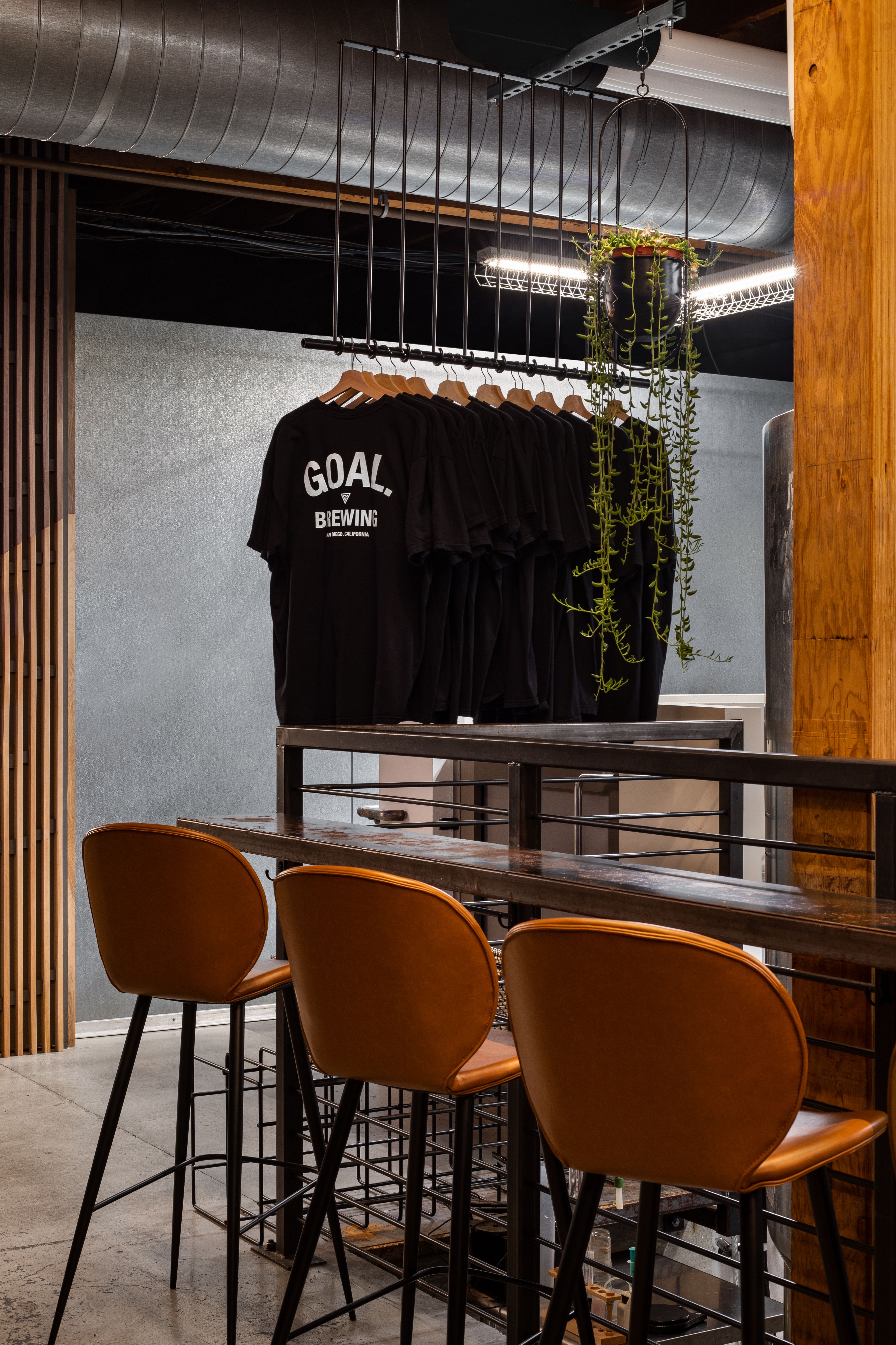 05 — Merch. A steel rail hangs the shirt inside the room: you don't have to leave the table to look at it.