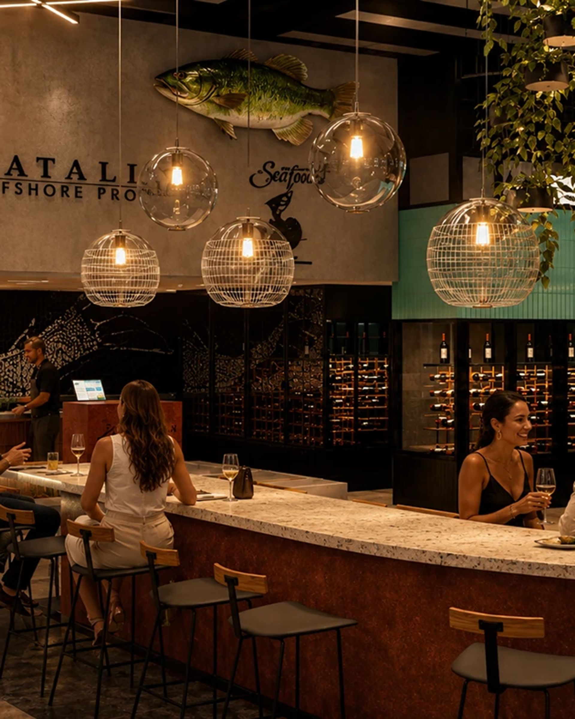 03 — Barra de vinos. Terrazo frío bajo el codo y botellas iluminadas atrás: aquí la espera también es parte del lugar.