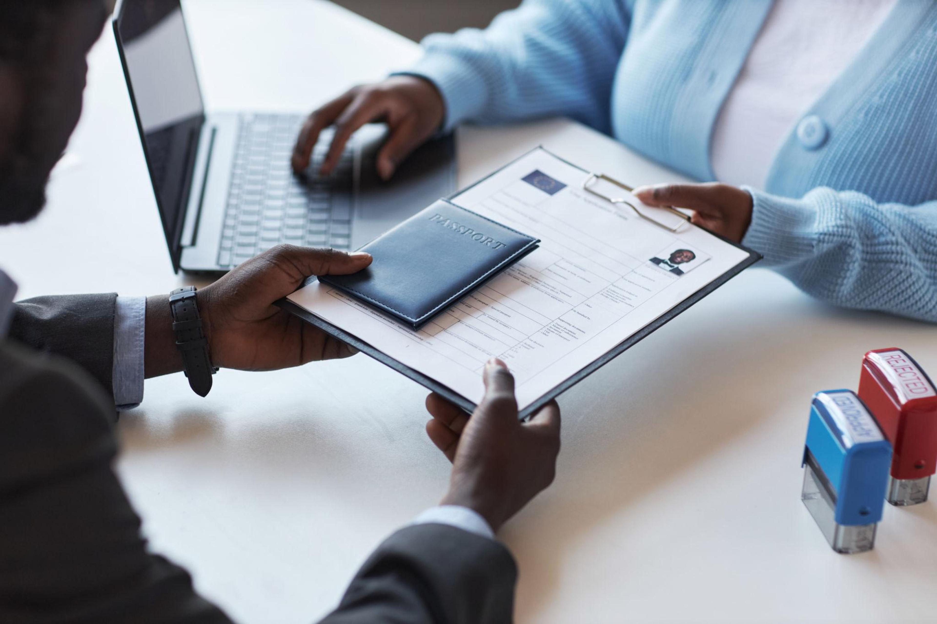 Travel documents consultant helping a corporate traveller prepare a passport, visa application and travel insurance.