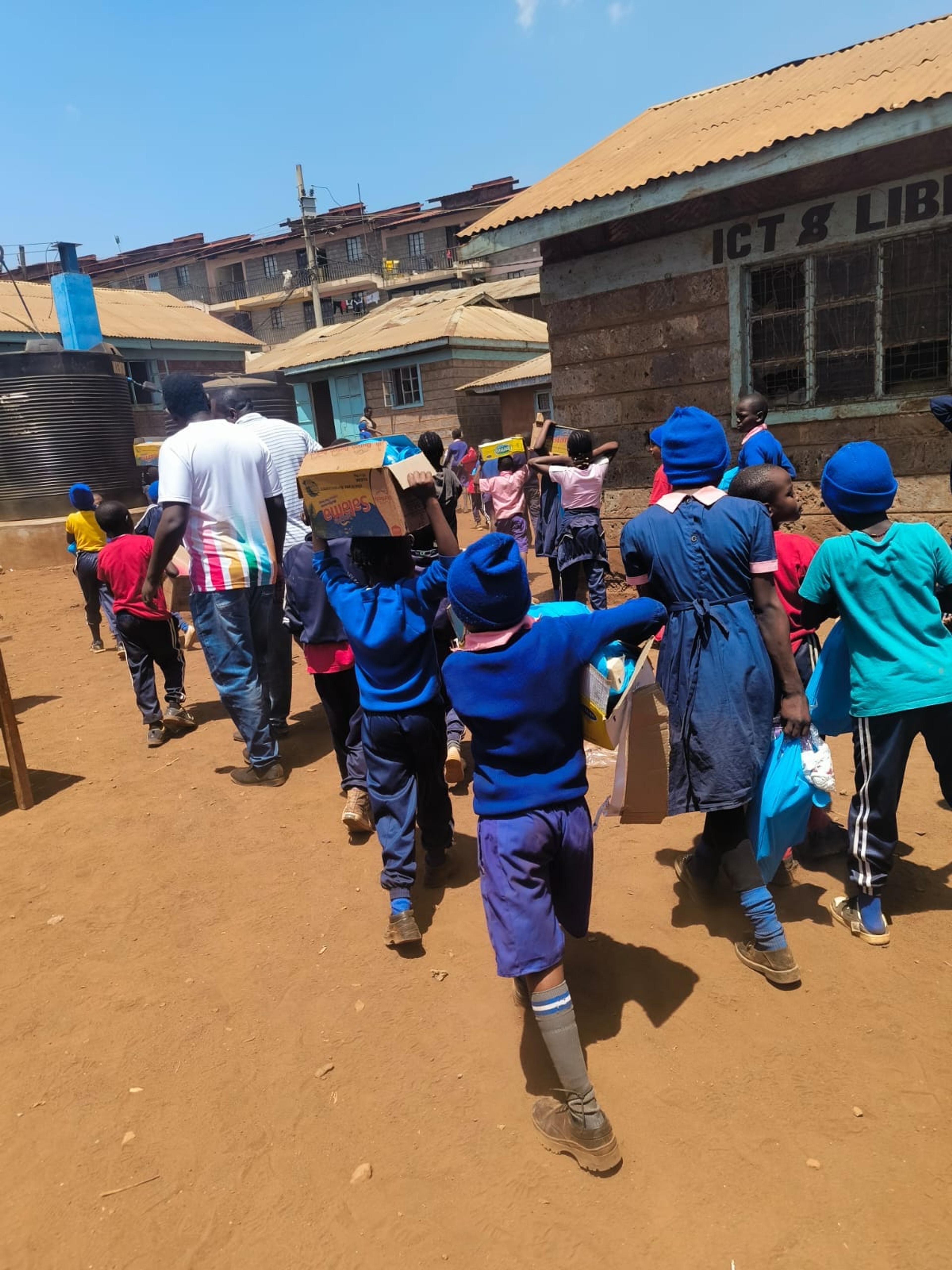 Pupils at Kibera YMCA School carrying care kits distributed during a Kendirita community outreach activity