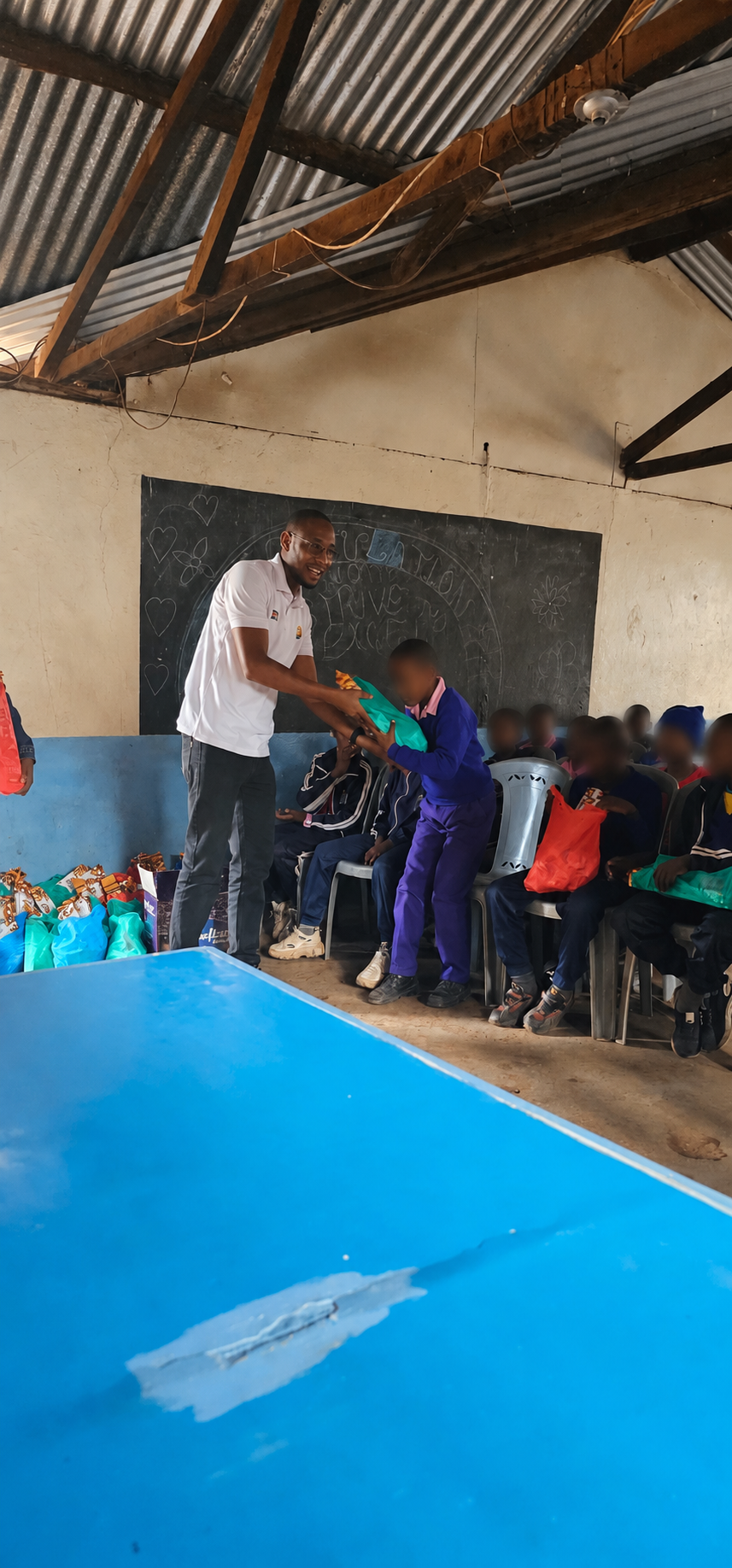 Kendirita team member distributing a care kit to a pupil at Kibera YMCA School