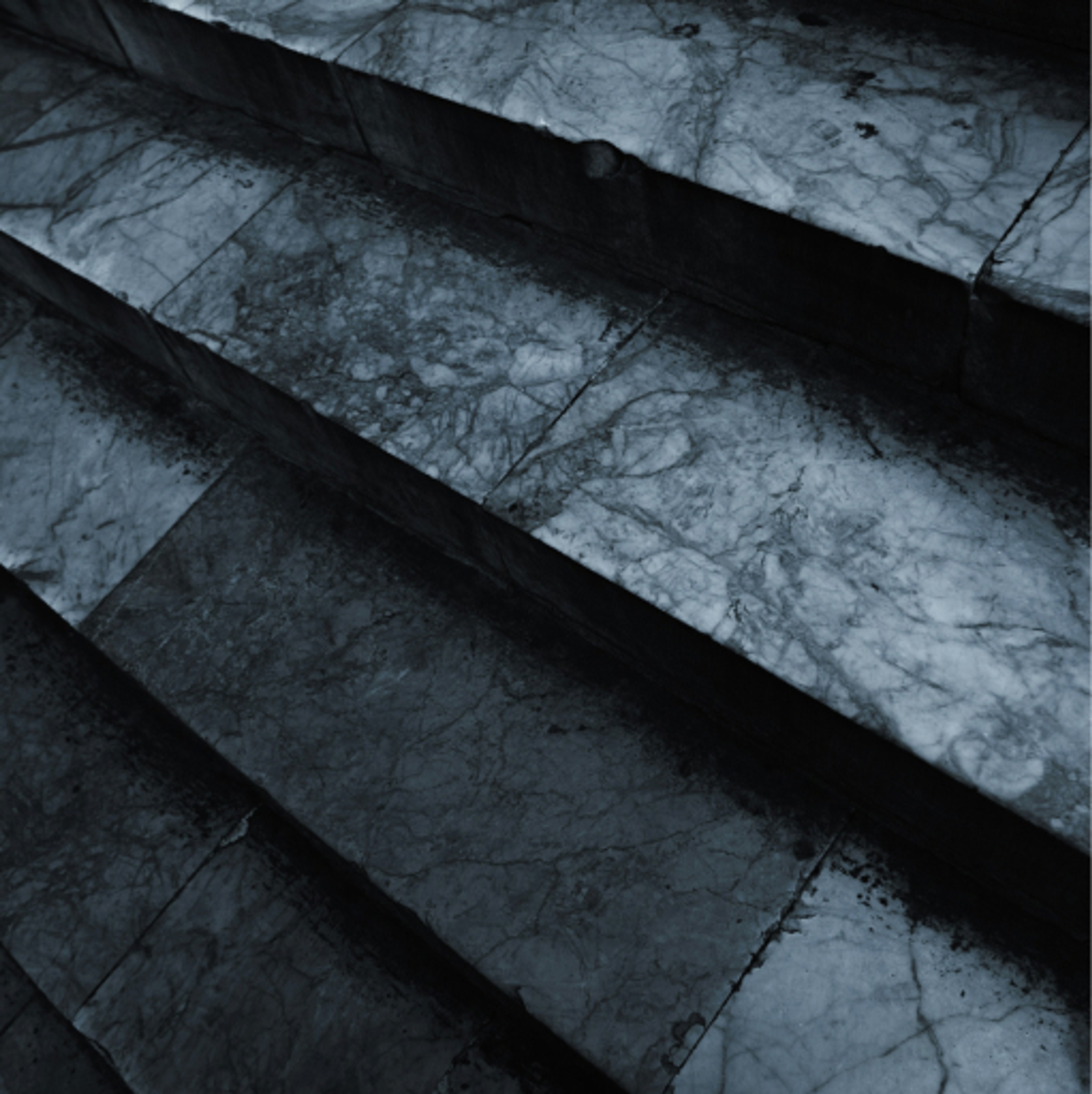 A close up view of blue and grey granite textured steps under moody lighting.