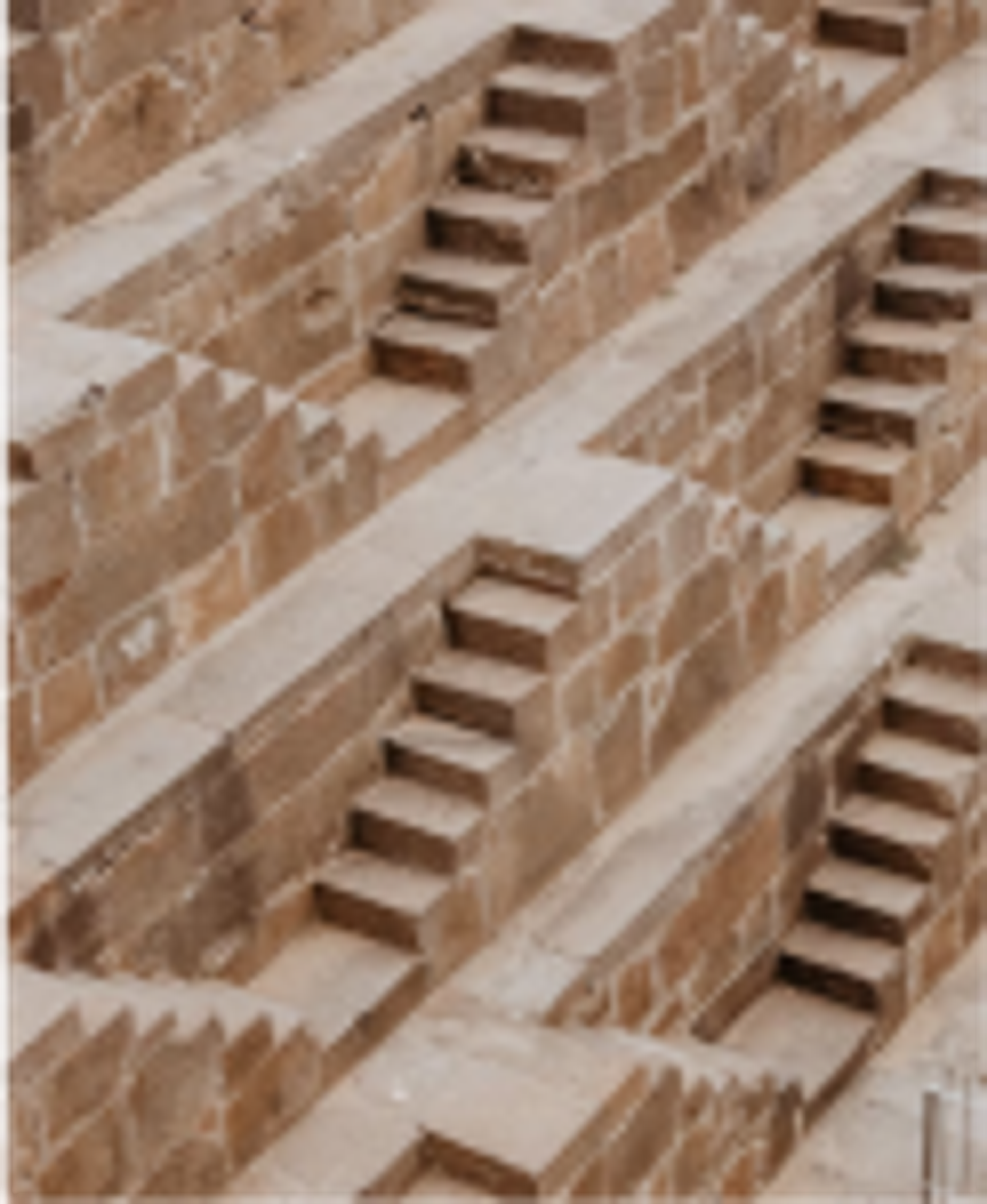 An aerial view of multi level, dual sided staircases made of an orange and brown stone.