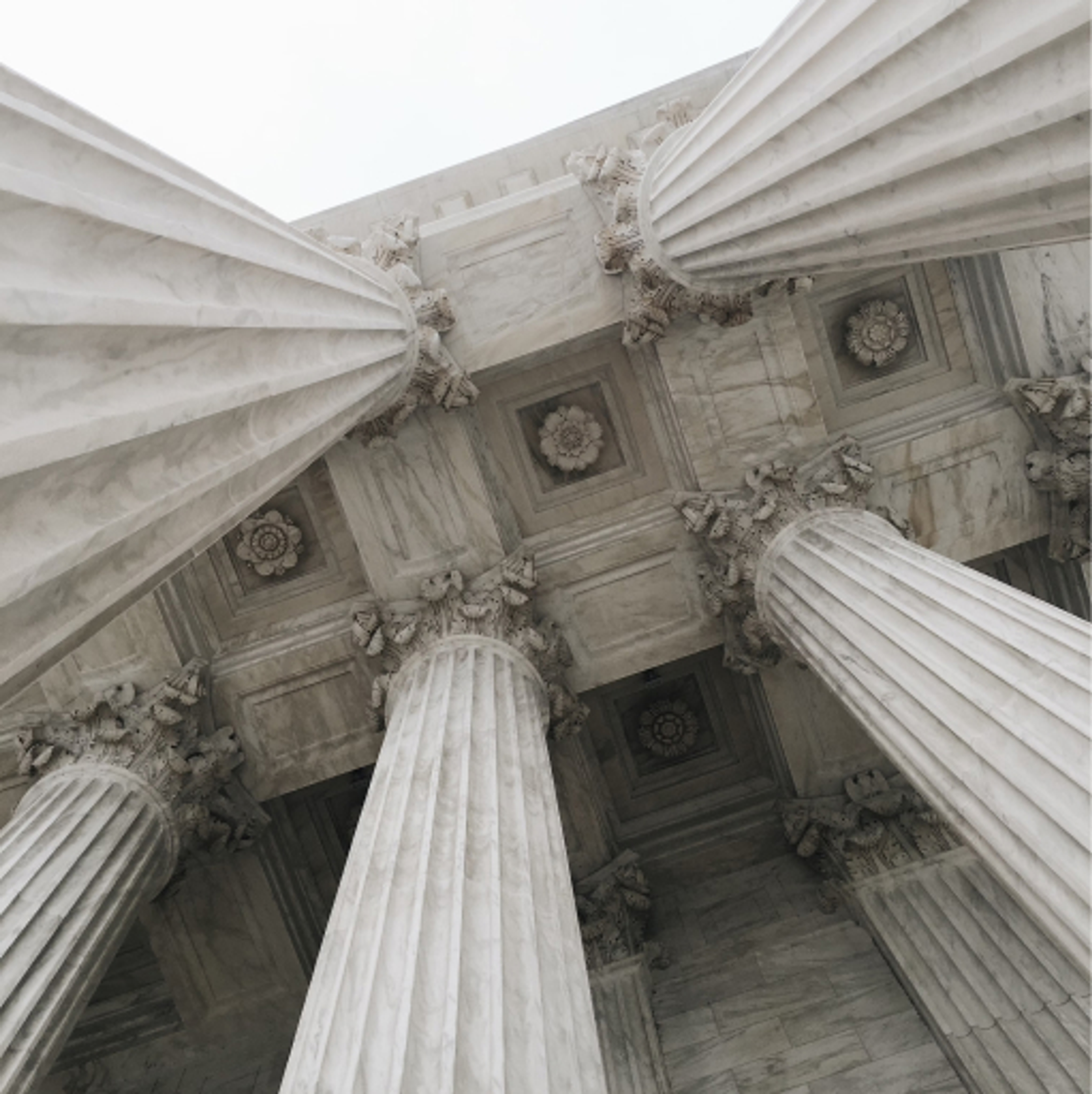 view looking up at an ornate ceiling and pillars of a towering marble structure.