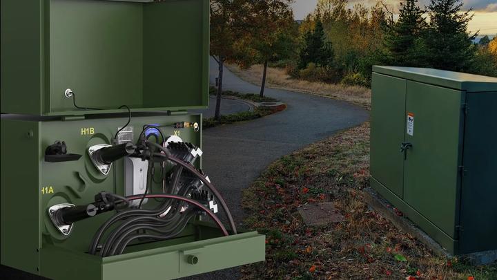 Open and closed green DTM-mounted electrical transformer cabinets installed beside paved pathway