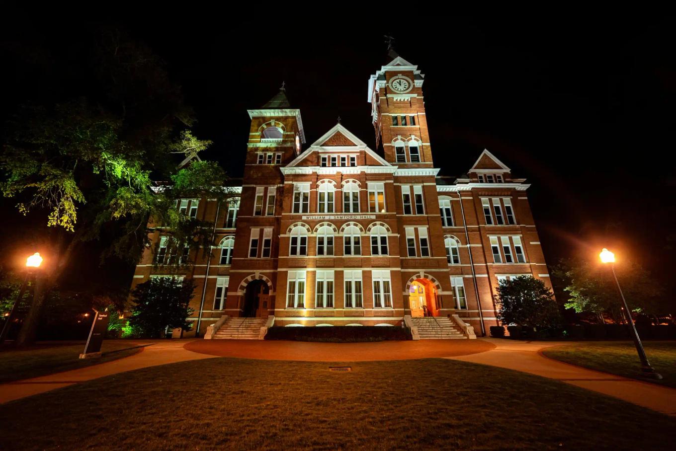Large historic brick building illuminated at night with exterior lights and symmetrical towers