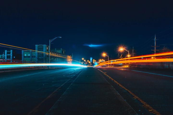 Long exposure view of vehicle light trails along an empty urban road at night with streetlights