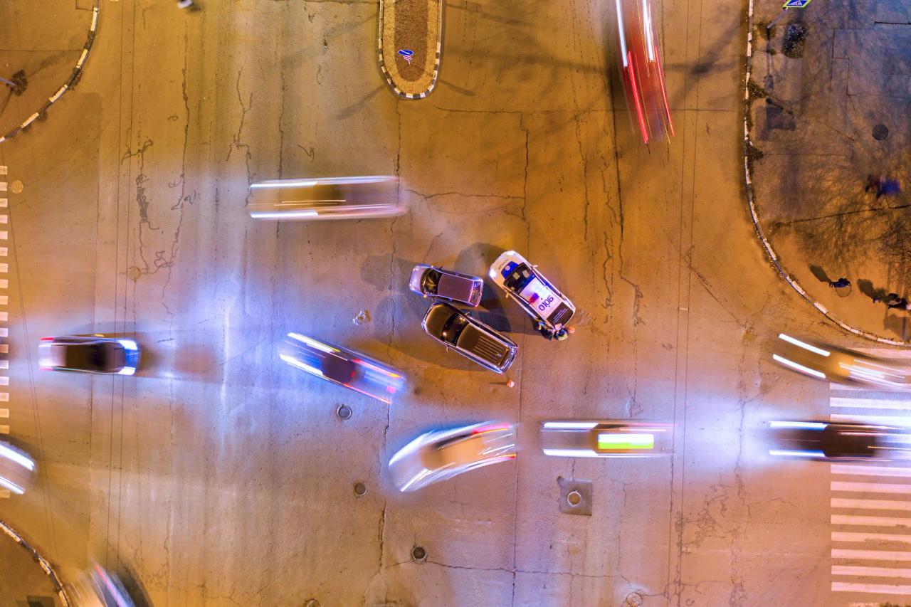 Overhead view of a busy intersection with moving vehicles and a police car at night