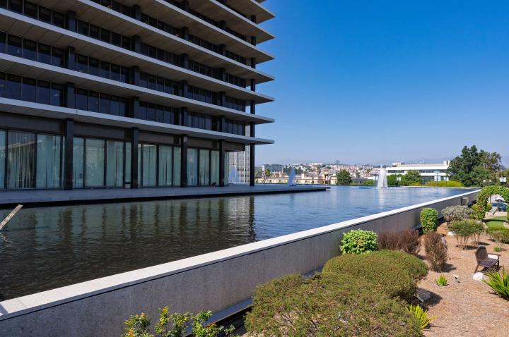 Modern office building beside a long reflecting pool with landscaped grounds of LA City