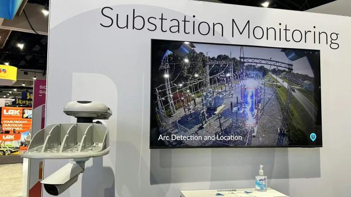 Trade show booth display showing substation monitoring system with UbiHub AI+ and screen labeled “Arc Detection and Location”