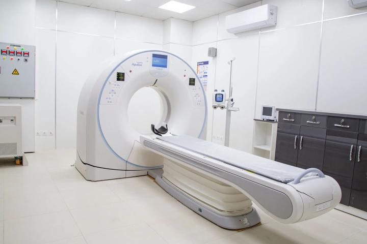 MRI scanner with patient table inside a clean hospital imaging room with cabinets and medical equipment