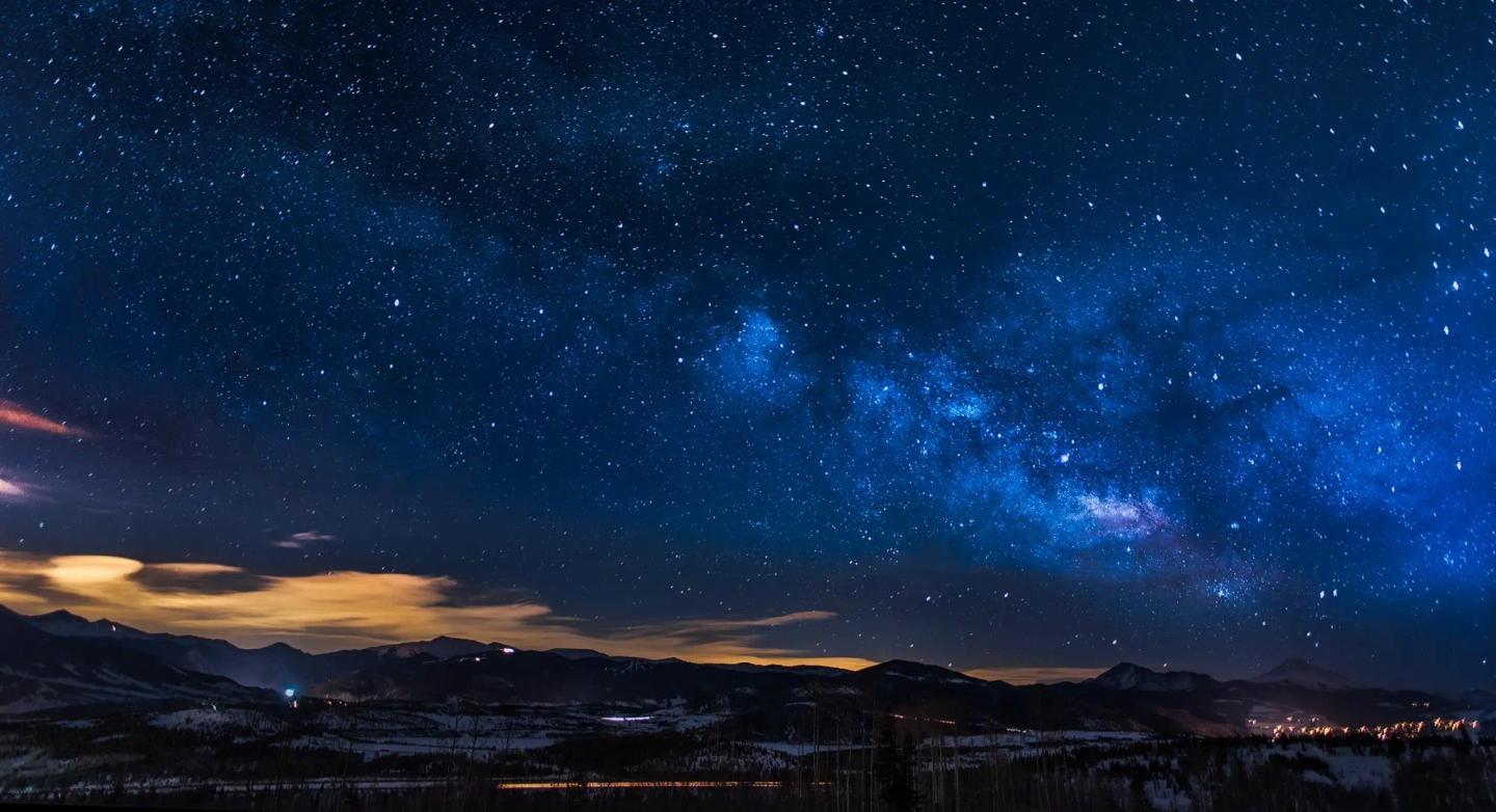 Arm of the Milky Way in a starry night sky above mountains