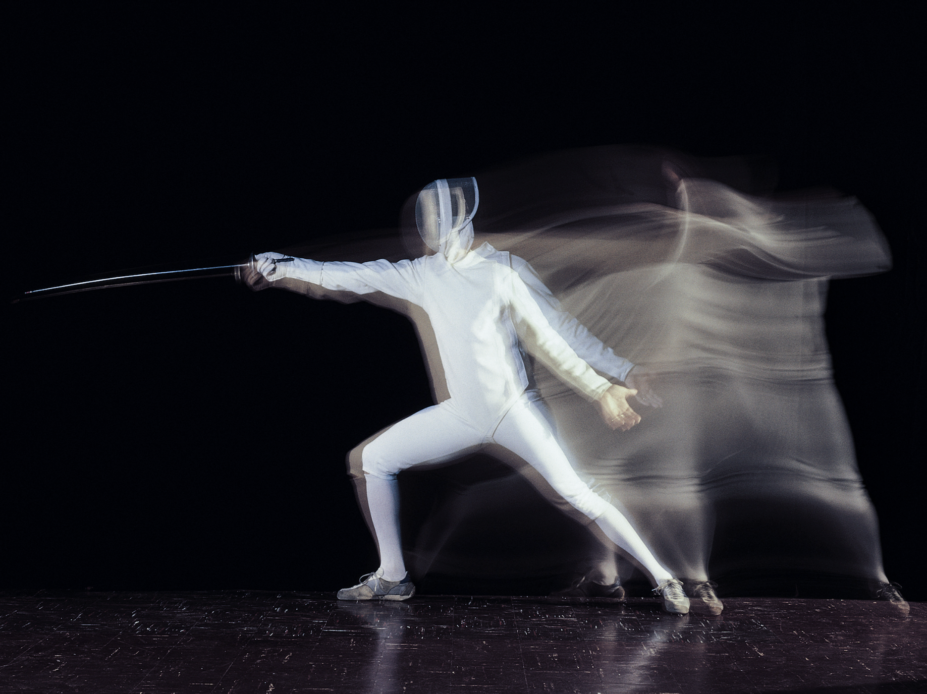 A person dressed in full fencing gear lunges forward 
