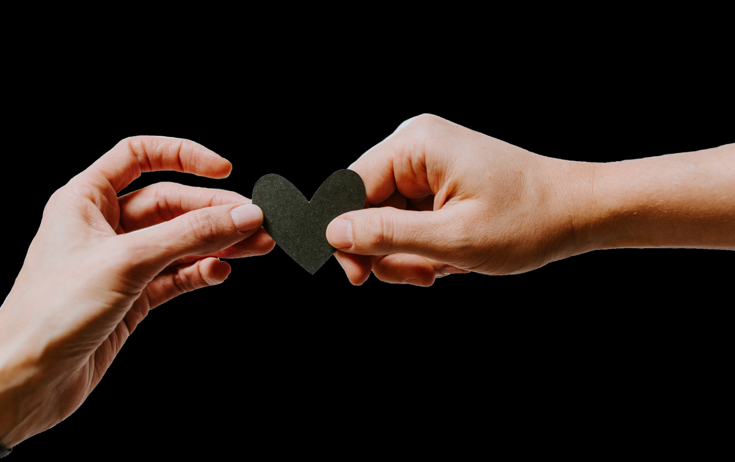 Two hands pass a black paper heart between each other