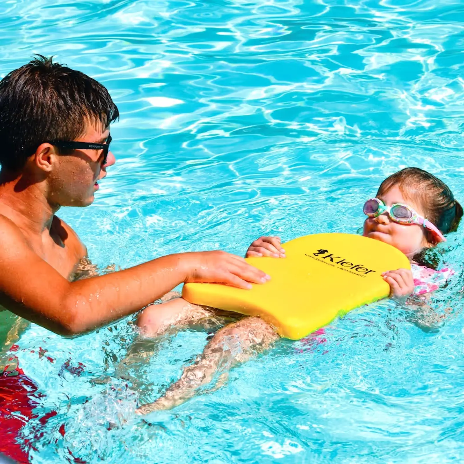 A Maplewood summer camp swim instructor and a little girl learning to swim in a shallow heated pool