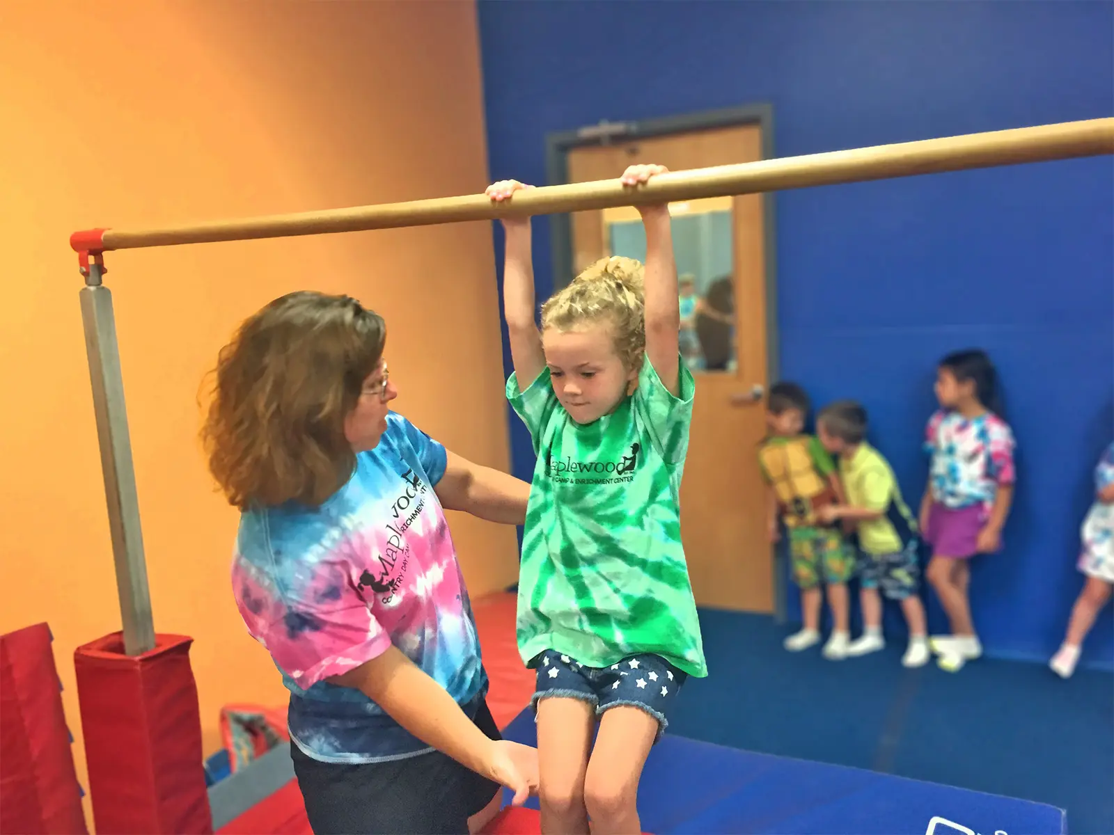 A woman teaching a child how to use a gymnastics bar
