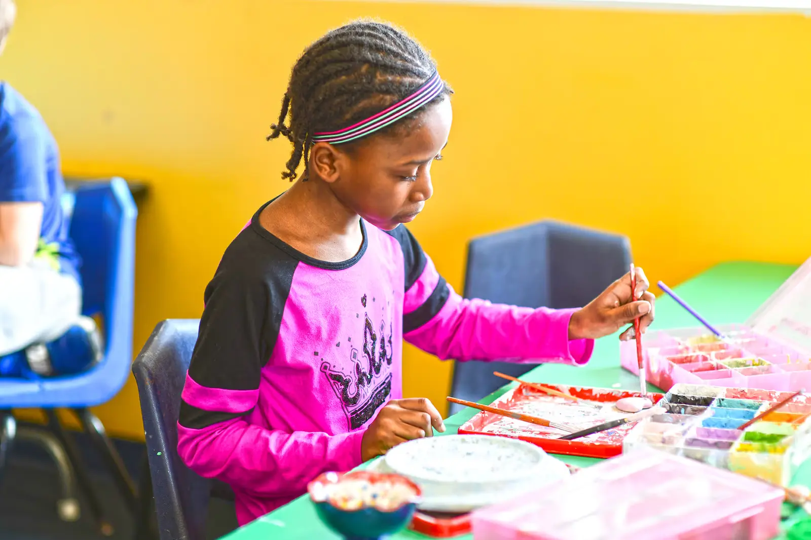 A little girl is painting on a table