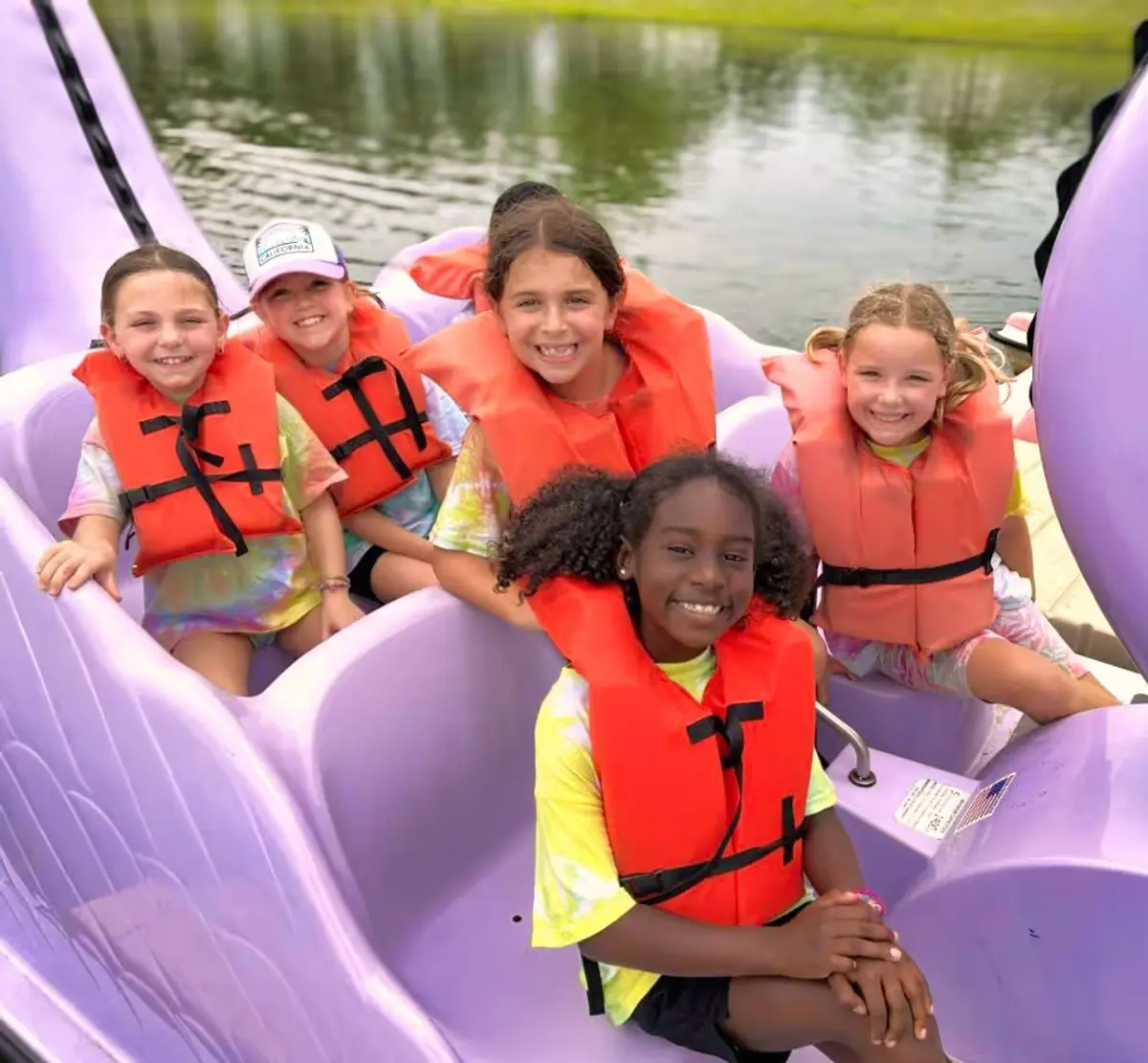 A group of children in life jackets on a boat in the shape of a swan