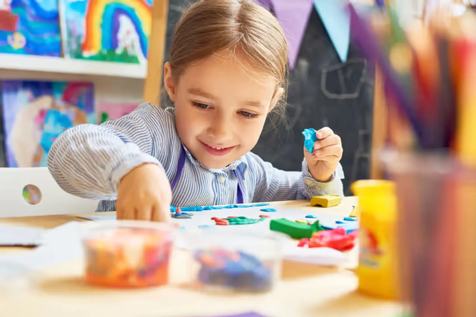 A little girl sits at a table happily playing with colorful shapes