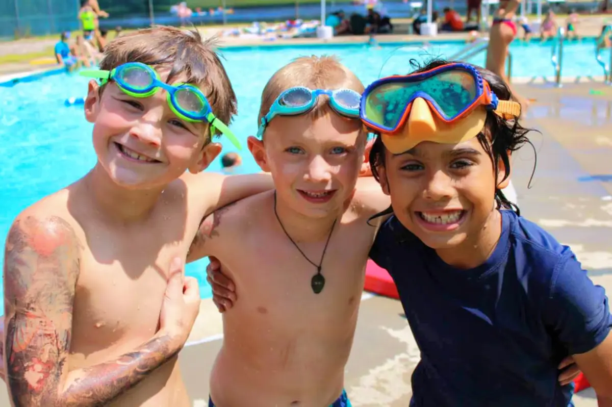 A group of smiling kids standing next to each other near a swimming pool
