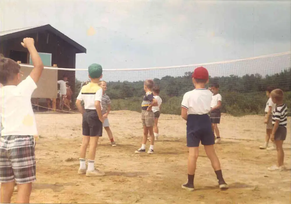Old photo from the 1950s of a group of young boys standing on top of a dirt sports field