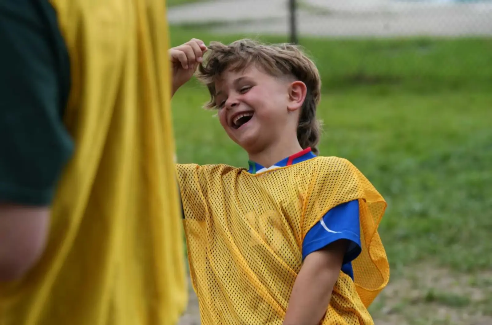 A laughing young boy in a yellow and blue soccer uniform