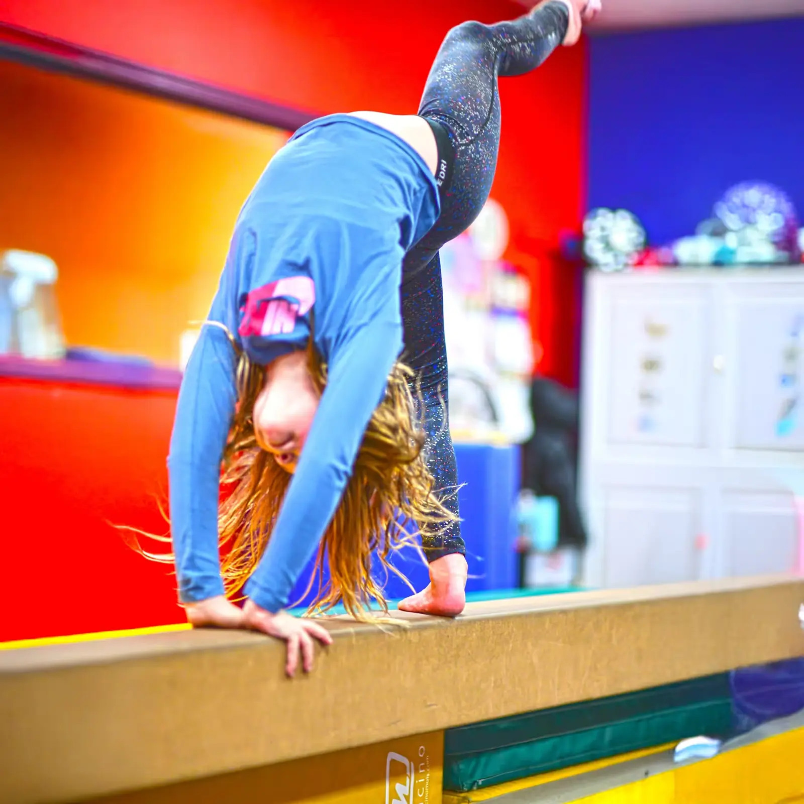 A girl doing a handstand on a balance beam