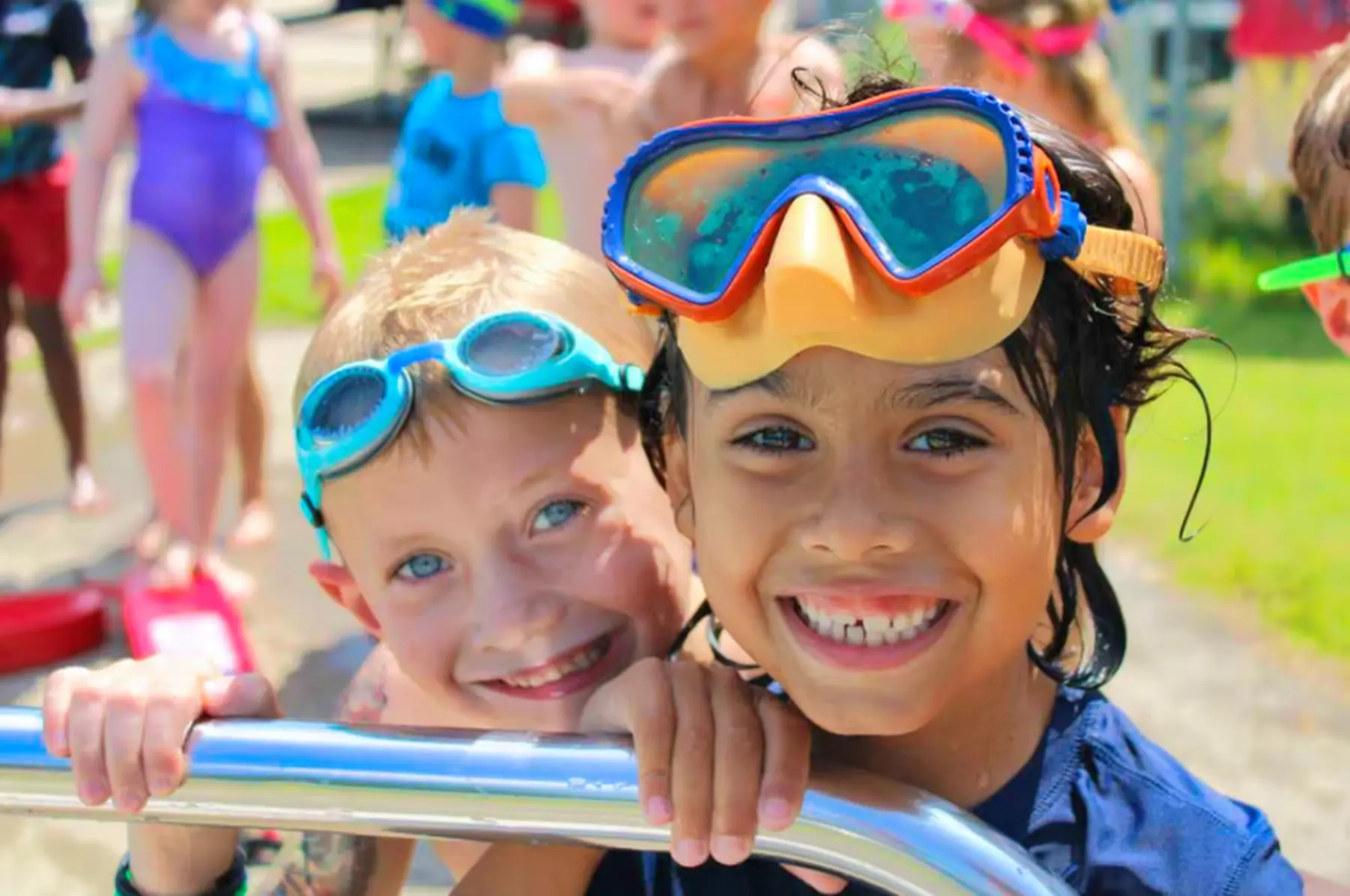 A group of smiling young children wearing swimming goggles
