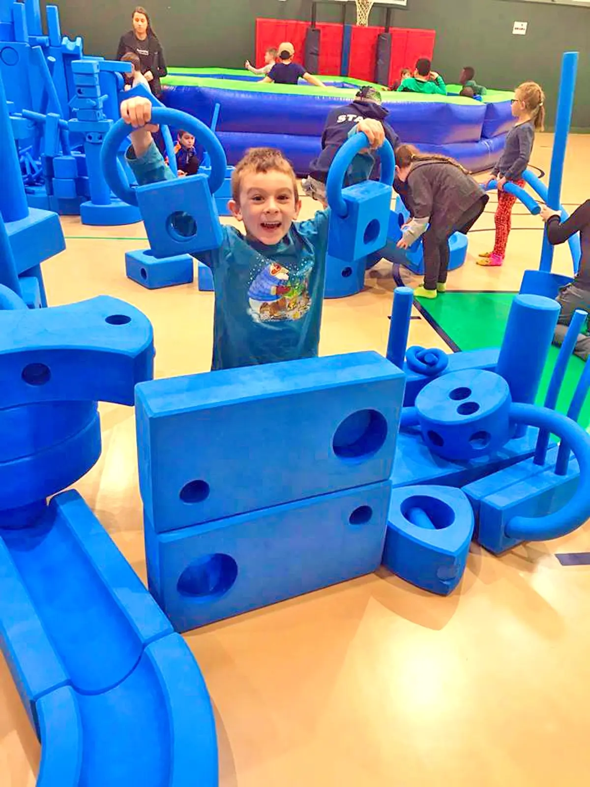 A young boy standing in front of a set of giant blue imagination play blocks