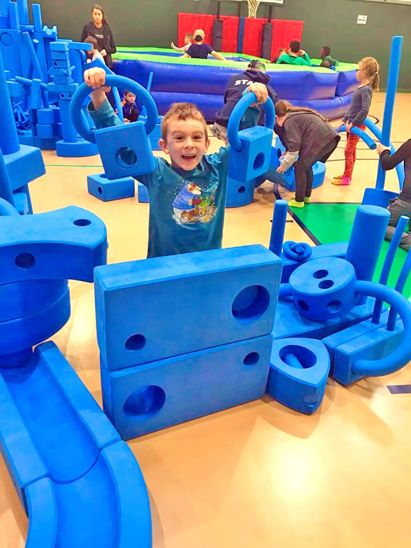 A young boy standing in front of a set of giant blue imagination play blocks