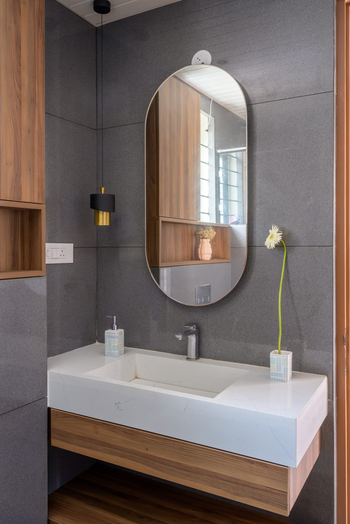 A wall-hung grey vanity with an oval mirror
