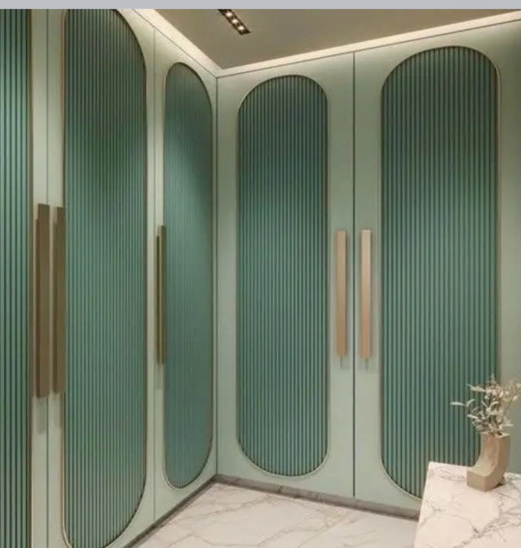 Deep green fluted arch wardrobe with brass pulls.