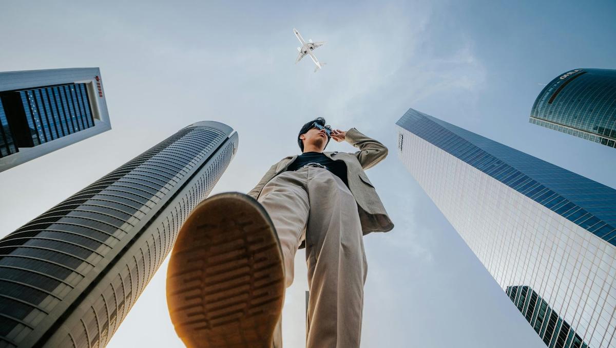 An unfazed professional stands outside with a plane overhead.